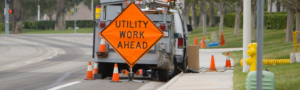 A construction sign on the side of the road saying 'utility work ahead'