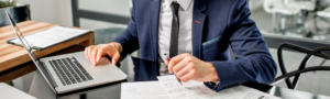 A man wearing a suit, working at his desk