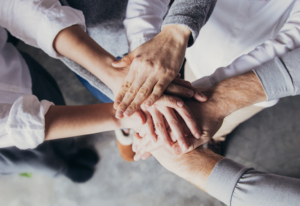 professionals all putting their hands together in gesture of playing as a team 