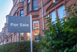 sale sign with town houses in the background